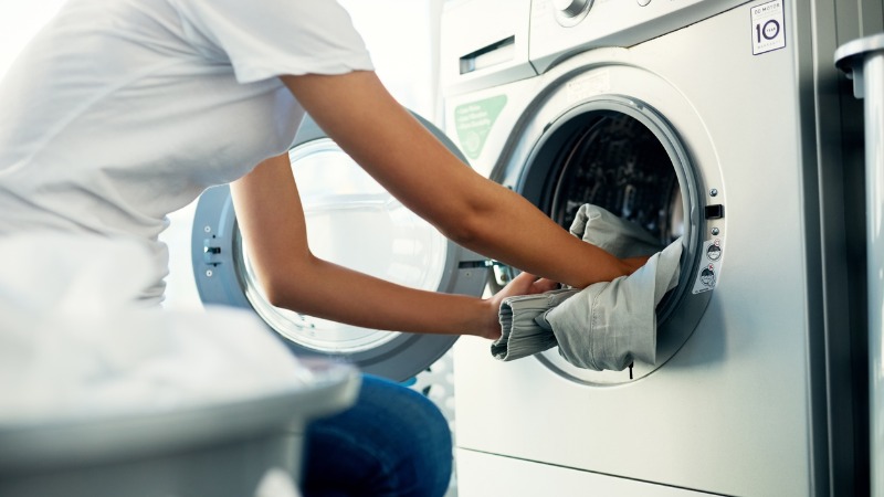 vrouw steekt wasgoed in wasmachine